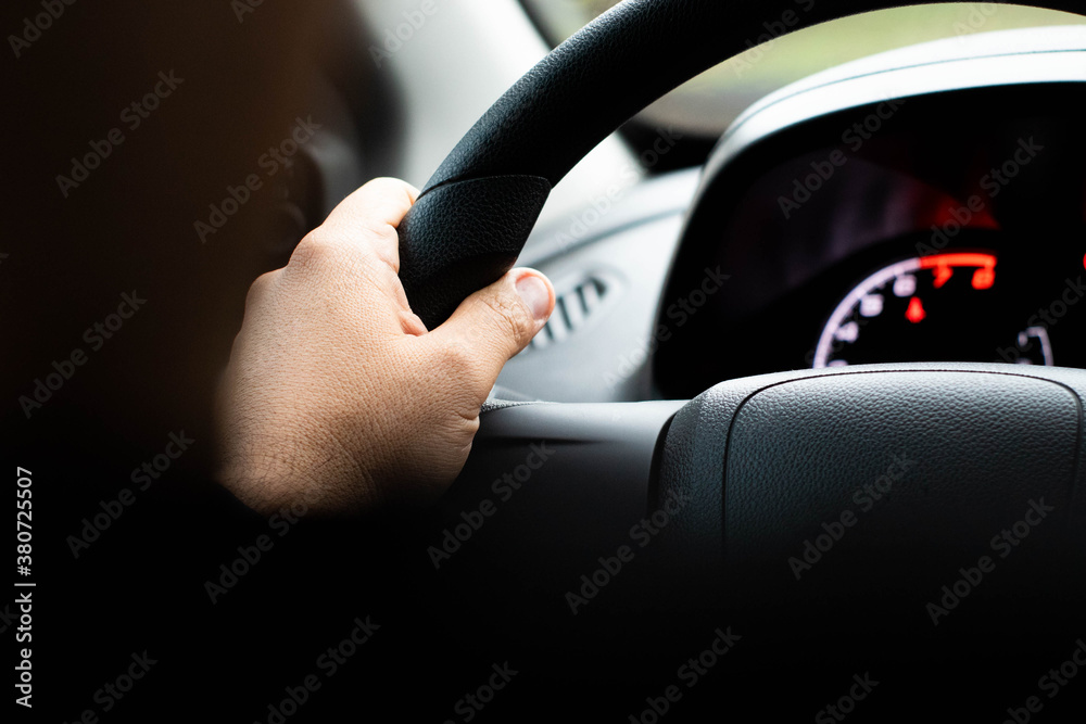man's hand on steering wheel, driving a car Selective focus / close up from a man's hand on a steering wheel in a rainy day