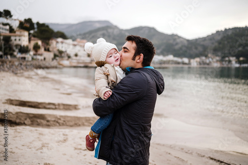 Father kissing baby on beach photo