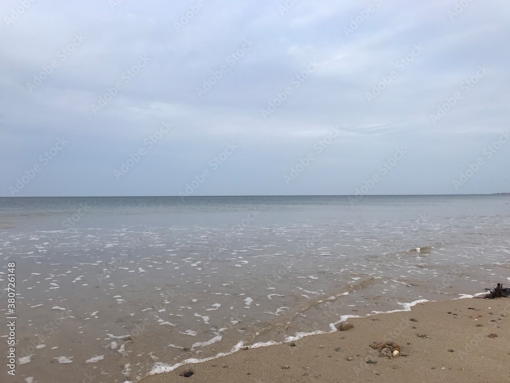Waves hitting the beach with a large cloudy sky 