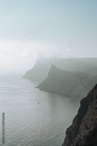 view of two rocky capes near the sea in sunset haze