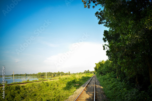 rail line passes through a forest (natural environment) and blue cloudy sky © Jonayet