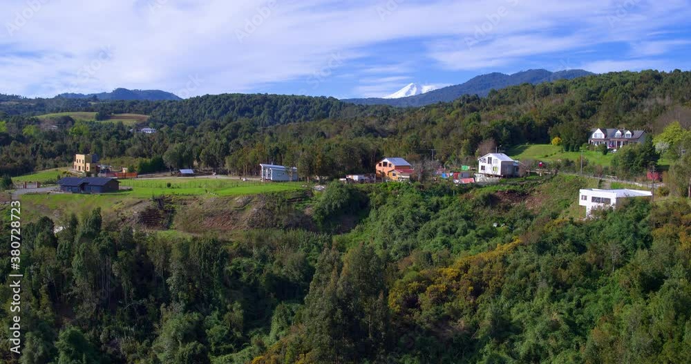 Aerial video with drone revealing the snowy summit of the Calbuco volcano, native forest and houses in rural areas Aerial video with drone revealing the snowy summit of the Calbuco volcano, native forest and houses in rural areas