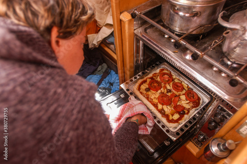 A woman is cooking in a tiny galley of the sailboat. photo