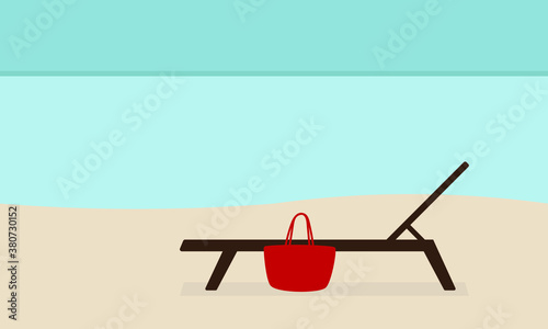 Deck chair and bag on the sand near the sea