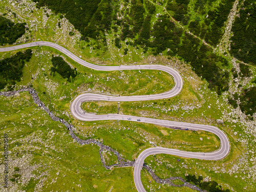 Winding road from high mountain pass, in summer time. Aerial view by drone . Romania
