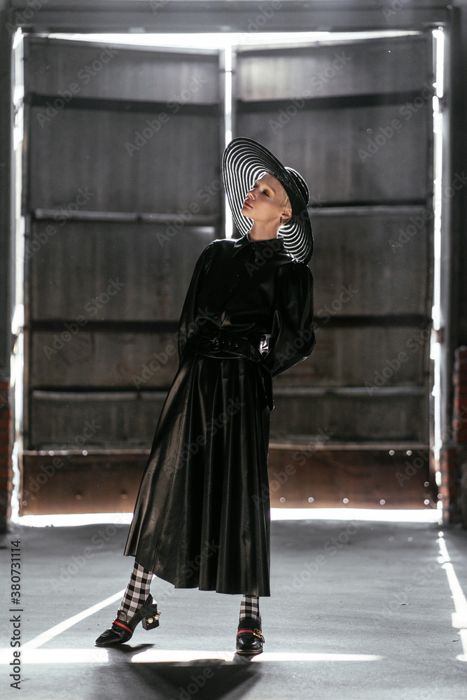 model in a wide-brimmed hat and a long dress in the backlight