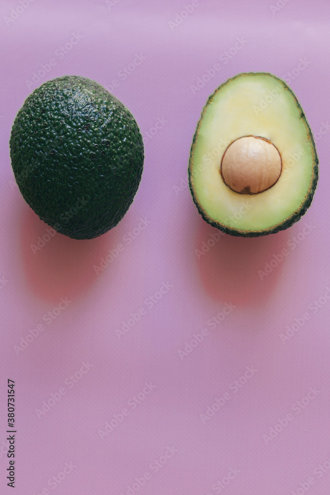 Organic avocado with seed, avocado halves and whole fruits on pink background. Top view. Square crop. Pop art design, creative summer food concept. Green avocadoes pattern in minimal flat lay style
