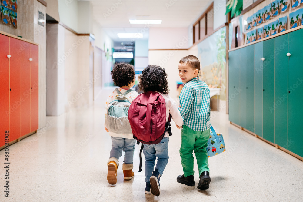 © Sergio Marcos/Stocksy - Happy kids walking in school corridor