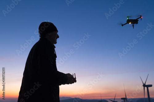 a smilling man is landing his drone in the setting sun photo