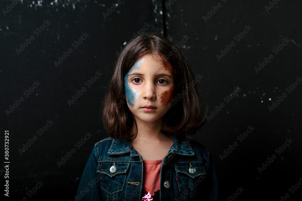 Kid with glitter on her face looking pensive Kid with glitter on her face looking pensive