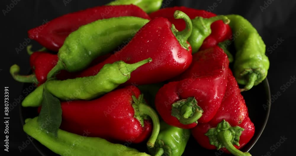Red and green pepper rotating on black background Red and green pepper rotating on black background
