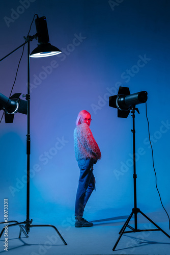 The girl with pink hair in a color light at the studio with light equipments