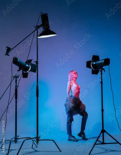 The girl with pink hair in a color light at the studio with light equipments photo