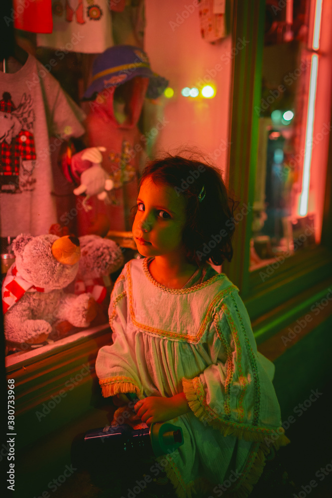 Girl sitting by a neon lighted store window Girl sitting by a neon lighted store window