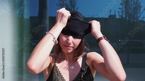 The girl removes a black balaclava from her face. An open face is a sign of freedom and strength. No fear of revealing the identity of the feminist. 