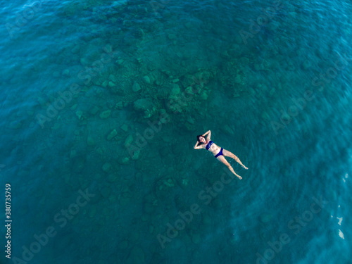 aerial image of a woman floating in dark turquoise water photo