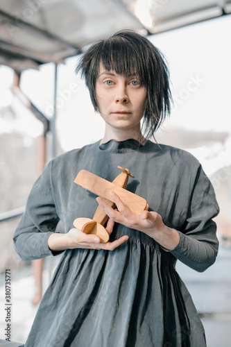 Black-haired caret girl holding the wooden figure of airplane in her hands photo