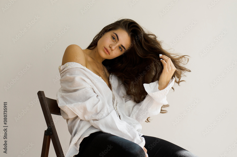 Young woman with long hair sitting on a chair Young woman with long hair sitting on a chair