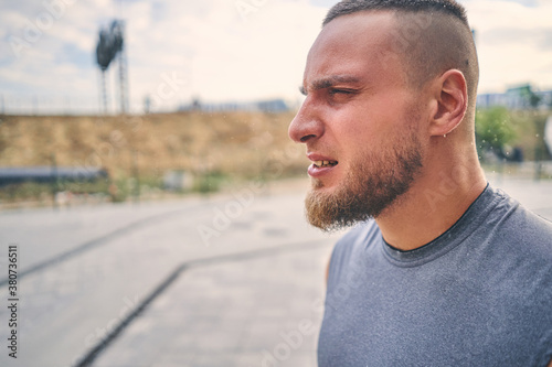 Portrait of a strong young athlete during training at city sports field. Sport concept