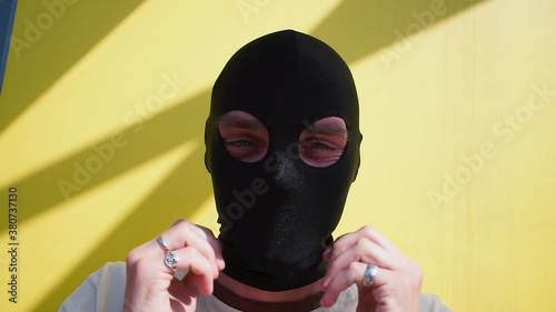 The man puts on a black balaclava over face. He makes dance moves with his hands. Motivation of positive incognito mood.