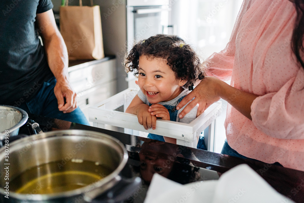 Happy daughter laughing while family is cooking vegan food at home Happy daughter laughing while family is cooking vegan food at home