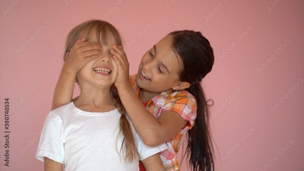 Two happy girls hugging each other isolated on pink background Two happy girls hugging each other isolated on pink background