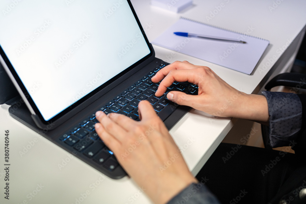 Side view of crop unrecognizable specialist sitting at table and typing on keyboard of laptop with empty white screen while working at workplace Side view of crop unrecognizable specialist sitting at table and typing on keyboard of laptop with empty white screen while working at workplace