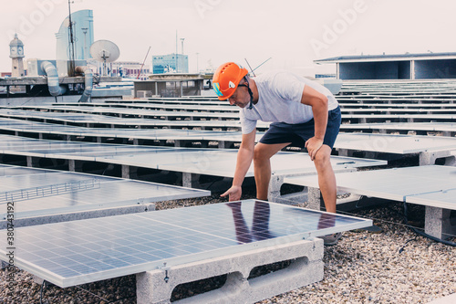 Print op canvas Serious male in helmet worker installing modern solar panels while working in in