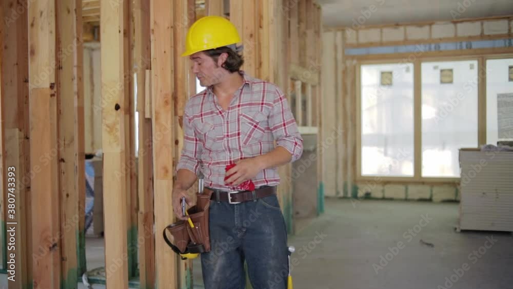 Construction worker indoors, coughing and feeling ill, using his cell phone to have a video call with his doctor. Construction worker indoors, coughing and feeling ill, using his cell phone to have a video call with his doctor.