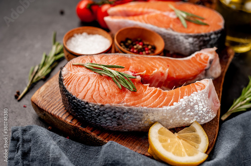  Raw fish salmon steak with lemon and rosemary on a stone background