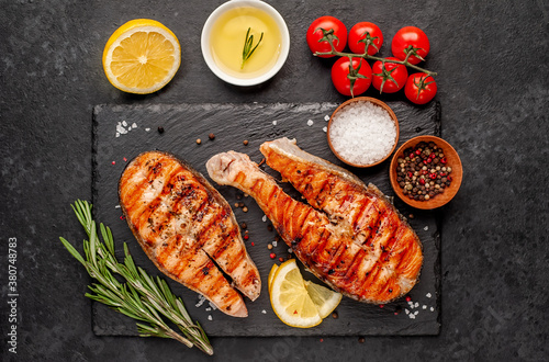 Grilled salmon steak with lemon and rosemary on a stone background	