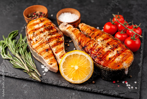 Grilled salmon steak with lemon and rosemary on a stone background