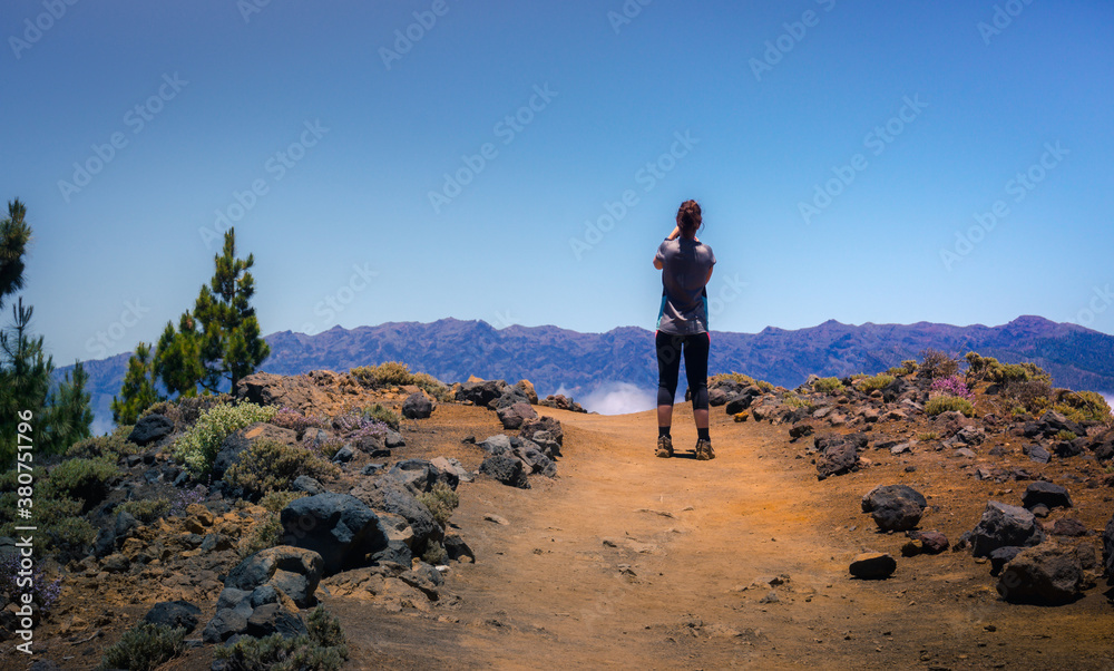 Back view of anonymous female traveler standing with outstretched arms on rocky hill in highlands and enjoying amazing view of clouds Back view of anonymous female traveler standing with outstretched arms on rocky hill in highlands and enjoying amazing view of clouds