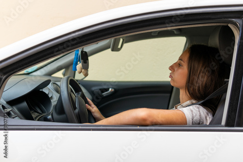 Side view of sad female driver sitting in modern car while stuck in traffic jam in city
