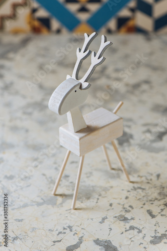 Closeup of handmade miniature wooden deer figurine painted in white color for Christmas decor photo