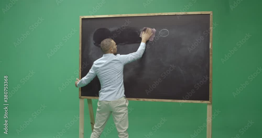 Studio, slow motion, green screen, young male teacher wipes off a vintage blackboard, London, UK Studio, slow motion, green screen, young male teacher wipes off a vintage blackboard, London, UK