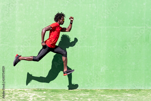 Side view of black sportsman in activewear in moment of jumping during intense workout on sunny day photo