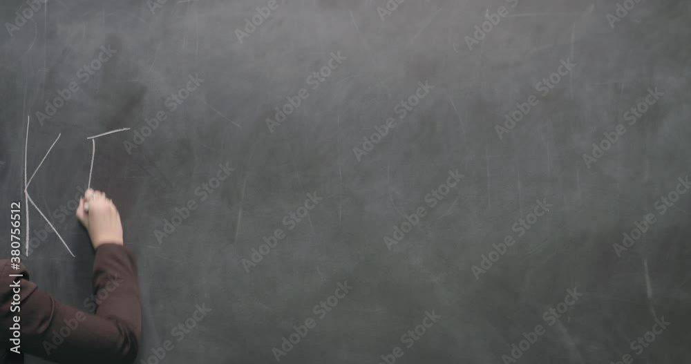 Studio, slow motion, close-up, young female teacher writes on a blackboard, London, UK Studio, slow motion, close-up, young female teacher writes on a blackboard, London, UK
