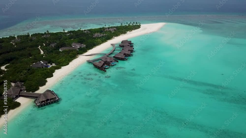 Wide lowering drone shot of private villas over the turquoise water .Hideaway resort in the Maldives. Wide lowering drone shot of private villas over the turquoise water .Hideaway resort in the Maldives.