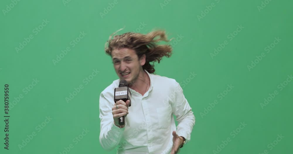 Studio, slow motion, green screen, young male reporter against the wind, London, UK Studio, slow motion, green screen, young male reporter against the wind, London, UK