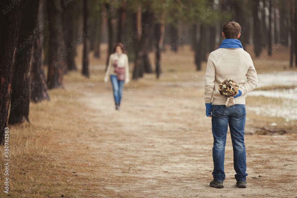 Obraz premium couple on winter walk in snow. Valentine's Day for couple in rustic style. Happy couple in love warming themselves with tea under a blanket in the arms of nature. Casual outfit with Blue accessories
