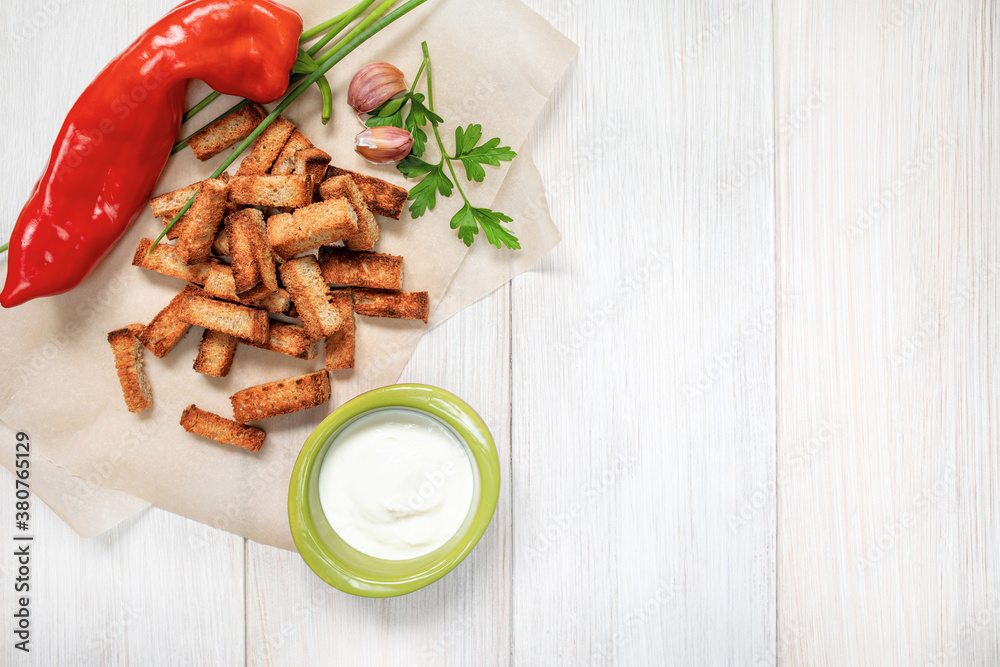 Slices of fried croutons with sour cream sauce, red pepper and garlic cloves close up on a white wooden boards. Flat lay. Copy space. Slices of fried croutons with sour cream sauce, red pepper and garlic cloves close up on a white wooden boards. Flat lay. Copy space.