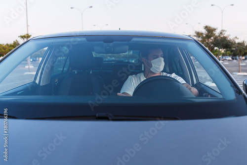 Chico con mascarilla dentro de coche en asiento de conductor © MiguelAngelJunquera