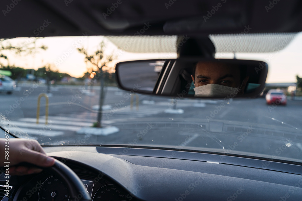 Chico con mascarilla dentro de coche en asiento de conductor