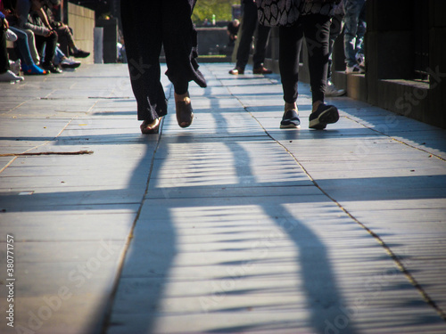 People walk and sit along the Southbank Promenade in summer. This riverside location has a great atmosphere amidst street performers, cafes, restaurants, river cruises, shops, arts and markets. 