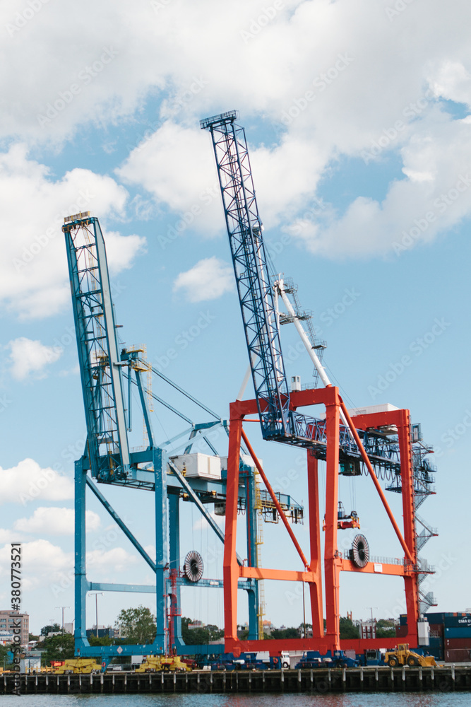 Vertical view of idle blue and red harbor cranes in harbor used for loading ships against blue sky Vertical view of idle blue and red harbor cranes in harbor used for loading ships against blue sky