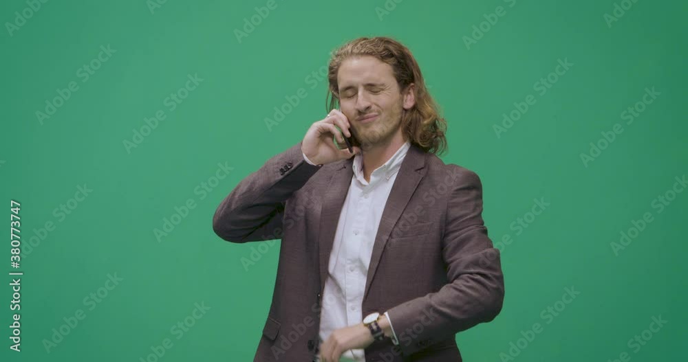 Studio, slow motion, green screen, a young man on the phone checks his watch, London, UK Studio, slow motion, green screen, a young man on the phone checks his watch, London, UK