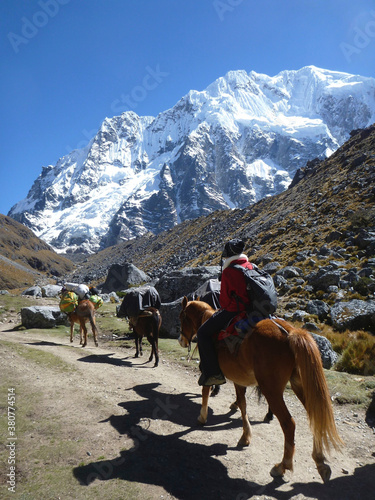 Horses and hikers on the Salkantay trek in Peru, with snow capped mountains in the distance