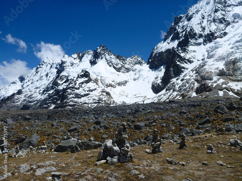 Scenic view of the rocky and mountainous terrain, including snow capped peaks, along the Salkantay trek in Peru, with cairns in the foreground © Jen