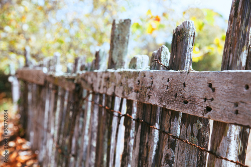 Rustic and rickety fall fence with rusty barbed wire photo